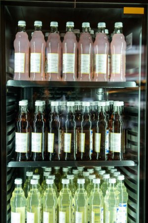 Foto de Primer plano del gabinete de exhibición refrigerado con varias bebidas embotelladas no alcohólicas dispuestas en los estantes metálicos - Imagen libre de derechos
