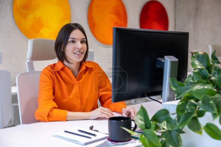 Foto de Joven trabajadora de oficina blanca concentrada sentada en el escritorio mirando el monitor de la computadora - Imagen libre de derechos