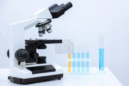 Téléchargez les photos : Image de différentes verreries de laboratoire avec liquide de couleur et microscope, microbiologiste ou chimiste lieu de travail. - en image libre de droit