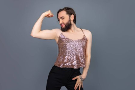 Téléchargez les photos : Mince attrayant transsexuel personne portant brillant débardeur ayant parfait corps levé bras montrant biceps posant isolé sur fond gris - en image libre de droit