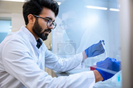 Téléchargez les photos : Scientifique barbu en lunettes et gants chirurgicaux testant des échantillons chimiques en fiole en laboratoire avec verrerie de laboratoire, science ou chimie recherche et développement. - en image libre de droit