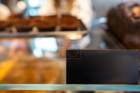 Foto de Enfoque selectivo de una etiqueta de precio negro en la vitrina de pastelería de vidrio bien iluminada con el fondo desenfocado - Imagen libre de derechos