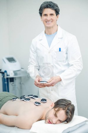 Foto de Tazas médicas. Terapeuta experimentado poniendo tazas médicas en los pacientes de nuevo - Imagen libre de derechos