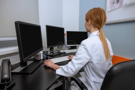 Photo for Professional scientist woman doctor wearing lab coat surrounded by monitors working on personal computers in stuff room. - Royalty Free Image