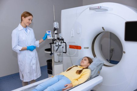 Foto de Paciente niña acostada en una mesa médica larga durante el procedimiento de resonancia magnética en el hospital, médico haciendo tomografía del niño en una clínica. - Imagen libre de derechos