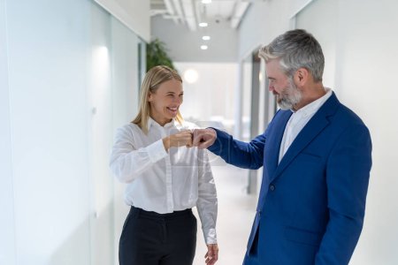 Photo for Joyful elegant business lady and her pleased male colleague giving one another the fist bumps - Royalty Free Image