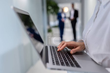 Photo for Cropped photo of a company employee typing on the portable computer standing in the corridor - Royalty Free Image