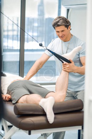 Foto de Hiperextensión. Paciente masculino con hiperextensión de pierna en un centro de rehabilitación - Imagen libre de derechos