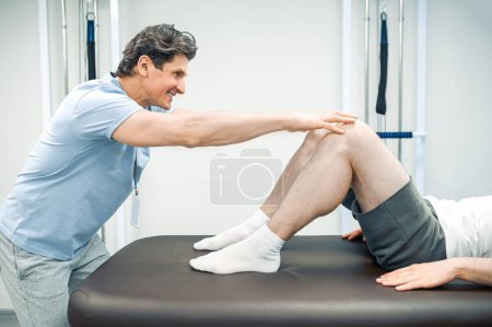 Photo for Legs rehabilitation. Male physical therapist working with patients legs - Royalty Free Image