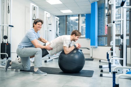 Photo for On fitball. Man having exersicing on fitball with instructor - Royalty Free Image