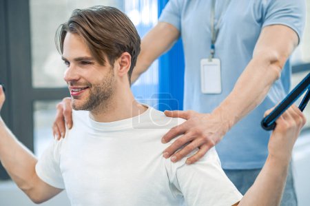 Photo for Physical therapy. Young man having na physical therapy with instructor in the rehabilitation center - Royalty Free Image