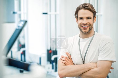 Téléchargez les photos : Dans un gymnase. Jeune homme en tenue de sport assis sur un appareil d'entraînement dans une salle de gym - en image libre de droit