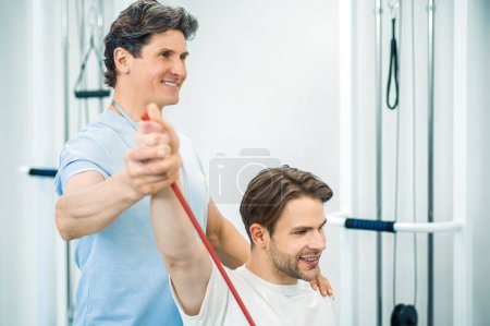 Photo for Physical therapy. Young man having a physical therapy session with a doctor - Royalty Free Image