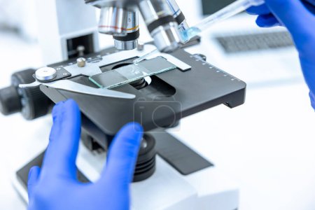 Nicht wiederzuerkennende Wissenschaftler, die im Labor mit technischer Ausrüstung und Mikroskop medizinische Proben untersuchen.
