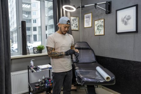 Téléchargez les photos : Dans le salon de tatouage. Jeune homme se préparant pour la session de tatouage - en image libre de droit