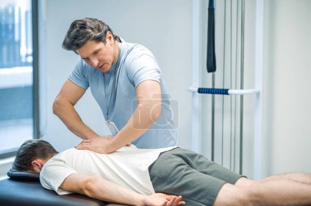 Foto de Masaje de espalda. Paciente masculino teniendo una sesión de rehabilitación masaje de espalda - Imagen libre de derechos