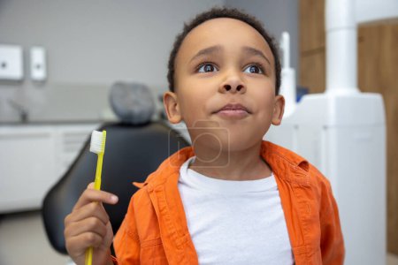 Foto de En odontología. Afro-americano chico buscando involucrado mientras se cepilla los dientes - Imagen libre de derechos