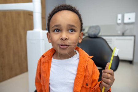 Foto de En odontología. Afro-americano chico buscando involucrado mientras se cepilla los dientes - Imagen libre de derechos