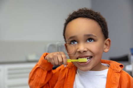 Photo for In dentistry. African-american boy looking involved while brushing his teeth - Royalty Free Image