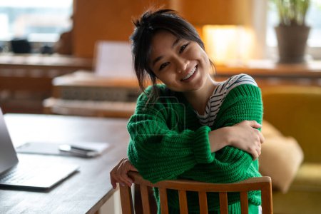 Foto de Chica feliz. Asiática chica en verde camisa en casa sonriendo muy bien - Imagen libre de derechos