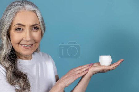 Photo for Face care product. Long-haired senior good-looking woman holding a jar of face cream - Royalty Free Image