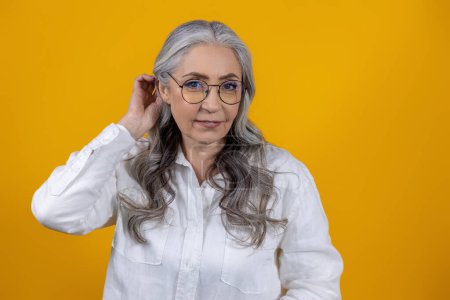 Téléchargez les photos : Femme avec des lunettes. Femme âgée intelligente en lunettes sur fond jaune - en image libre de droit