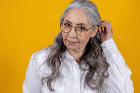 Téléchargez les photos : Femme avec des lunettes. Femme âgée intelligente en lunettes sur fond jaune - en image libre de droit