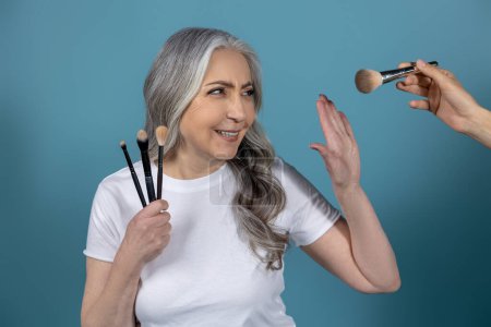 Téléchargez les photos : Conseils beauté. Belle femme âgée souriante faisant du maquillage - en image libre de droit