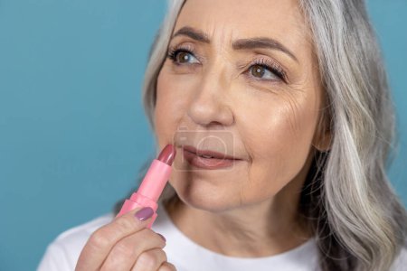 Photo for Makeup. Beautiful aging woman with lipstick doing makeup - Royalty Free Image