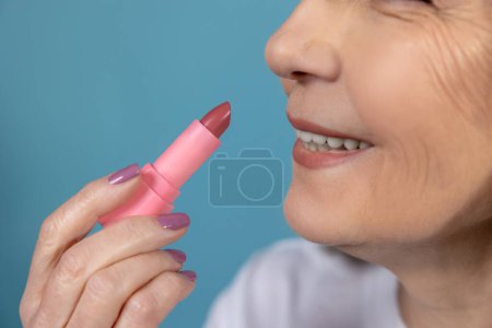 Photo for Makeup. Beautiful aging woman with lipstick doing makeup - Royalty Free Image