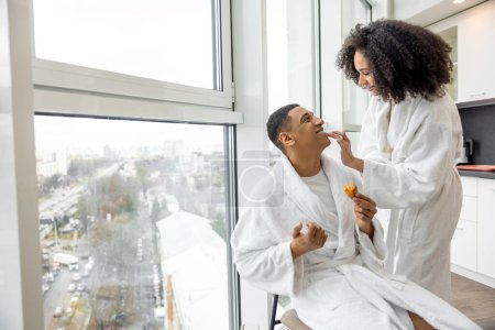 Photo for Lovely morning. Young couple in bath robes having breakfast and having fun - Royalty Free Image