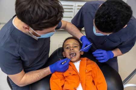 Foto de En odontología. Dentista y su asistente tratando dientes de niños - Imagen libre de derechos