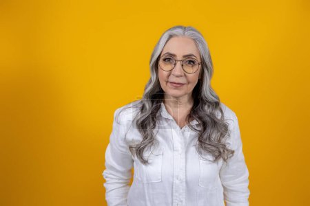 Photo for Woman on yellow background. Long-haired beautiful seniort woman standing on yellow background - Royalty Free Image