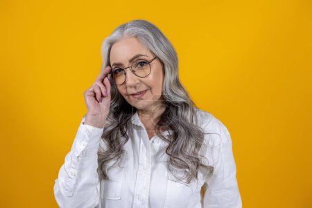 Foto de Mujer con anteojos. Mujer mayor inteligente en gafas graduadas sobre fondo amarillo - Imagen libre de derechos