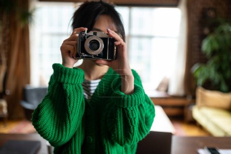 Photo for Young photographer. Girl in green shirt with a camera in hands - Royalty Free Image