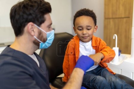 Téléchargez les photos : Docteur et patient. Mignon petit garçon se sentant détendu après avoir parlé avec son dentiste - en image libre de droit