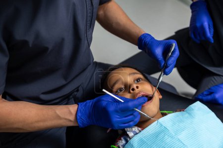 Téléchargez les photos : En dentisterie. Dentiste traitant les dents de garçons à la peau foncée - en image libre de droit