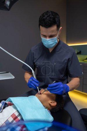 Foto de En odontología. Hombre médico buscando concentrado mientras que el tratamiento de los dientes chicos - Imagen libre de derechos