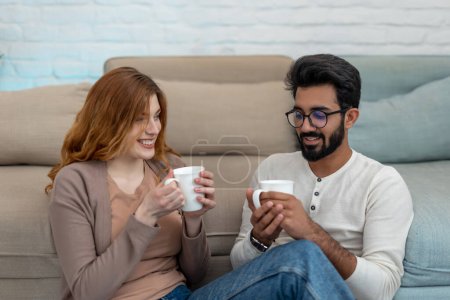 Photo for Romantic couple drinking coffeee at home relaxing communicating in cosy living room. - Royalty Free Image