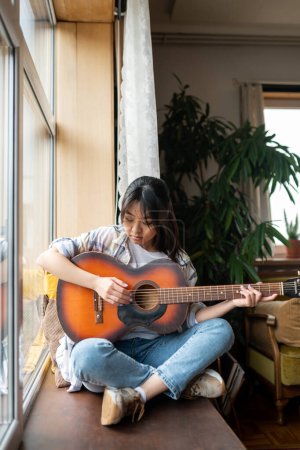 Foto de Chica con guitarra. Linda chica asiática joven con guitarra en casa - Imagen libre de derechos