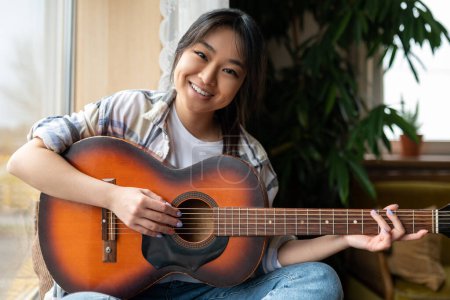 Photo for Girl with guitar. Cute young asian girl with guitar at home - Royalty Free Image