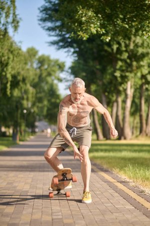 Téléchargez les photos : Homme sportif avec longboard équitation dans un parc de la ville - en image libre de droit