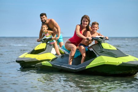 Photo for Father, mother, daughter and son racing on jet-skis enjoying watercraft in ocean, active summertime. - Royalty Free Image