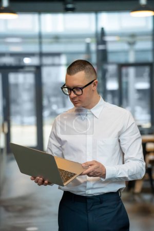 Téléchargez les photos : Jeune homme confiant occupé travaillant à distance dans un café tenant des fenêtres d'ordinateur portable en arrière-plan. - en image libre de droit