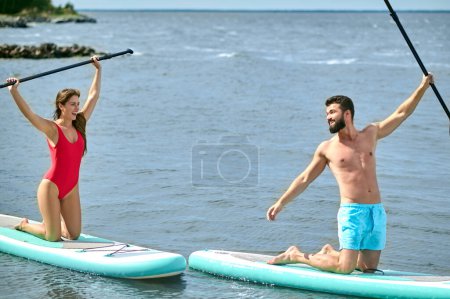 Téléchargez les photos : Couple de touristes jeune homme et femme s'amuser à pagayer en mer, profiter des vacances d'été, mode de vie actif. - en image libre de droit