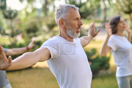 Photo for Mature group of people workout and practice tai chi in the park. - Royalty Free Image