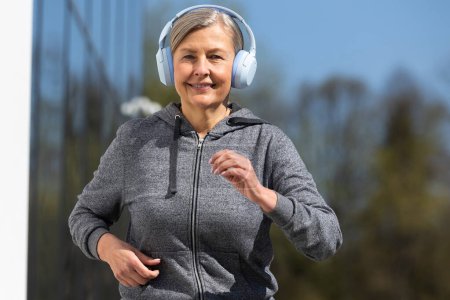 Photo for Morning in the park. Woman in sportswear and headphones having morning run in the park - Royalty Free Image