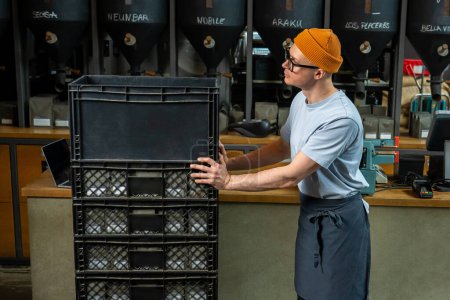 Foto de Camarero barista con sombrero y vasos descarga nuevo lote de café para la elaboración de café en la cafetería. - Imagen libre de derechos