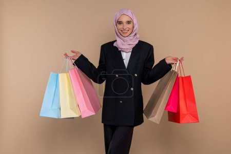 Téléchargez les photos : Après les courses. Jeune femme musulmane élégante avec des sacs à provisions à la recherche satisfait - en image libre de droit