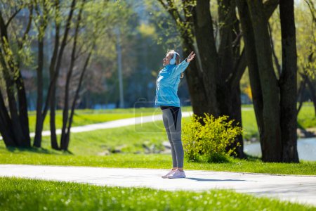 Foto de Saludo al sol. Mujer de pie en el camino del parque con los brazos en alto - Imagen libre de derechos